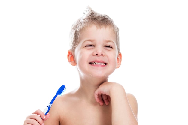 Menino sorridente alegre com uma escova de dentes na mão Higiene diária e cuidados pessoais Isolado em fundo branco