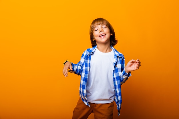 Menino sorridente alegre pulando e se divertindo na parede amarela. conceito de escola.