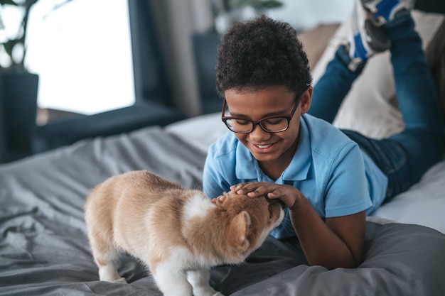 Menino sorridente brincando com um cachorrinho e parecendo feliz