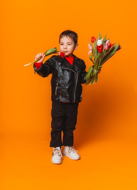 Menino sorridente com buquê de flores de primavera de tulipas isoladas em amarelo garotinho segurando tulipas