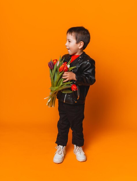 Menino sorridente com buquê de flores de primavera de tulipas isoladas em amarelo garotinho segurando tulipas