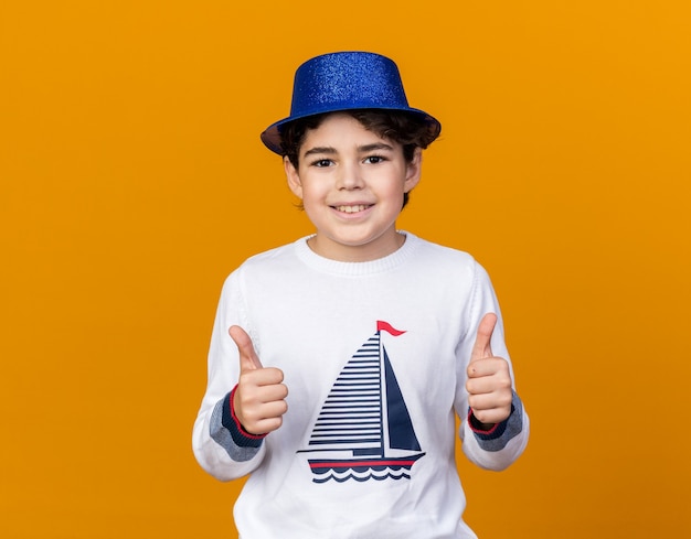 Menino sorridente com chapéu de festa azul mostrando os polegares para cima