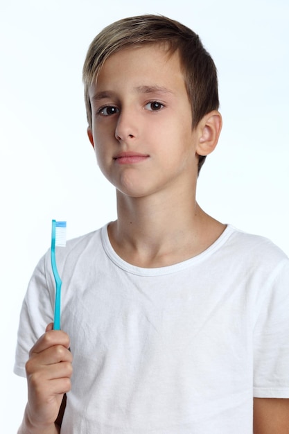 Menino sorridente com escova de dentes na mão isolada no fundo branco