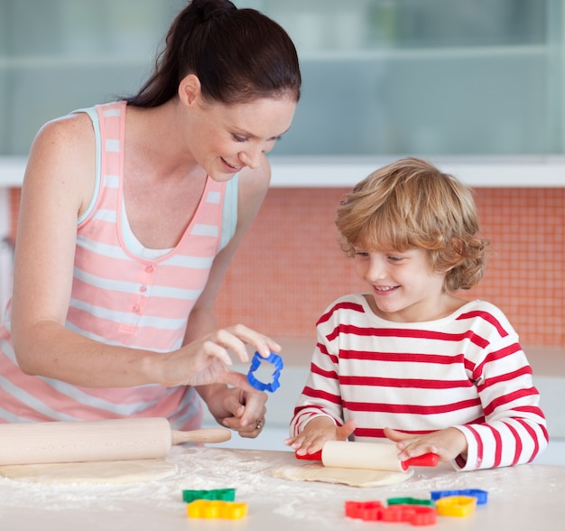 Menino sorridente com sua mãe e cortador de bolachas