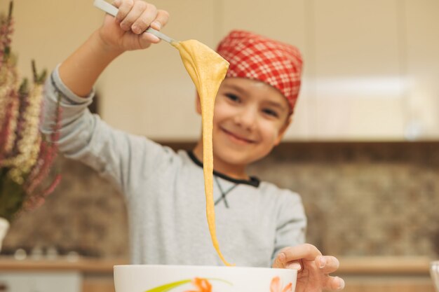 Menino sorridente, cozinhar massa para bolo