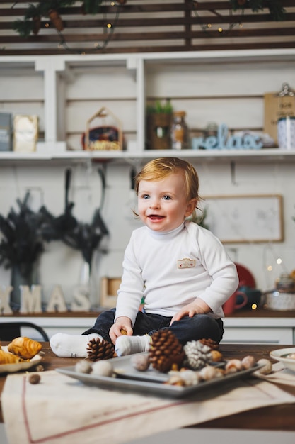 Menino sorridente de 1 ano de idade no fundo das decorações de Natal em casa Atmosfera de Ano Novo em casa