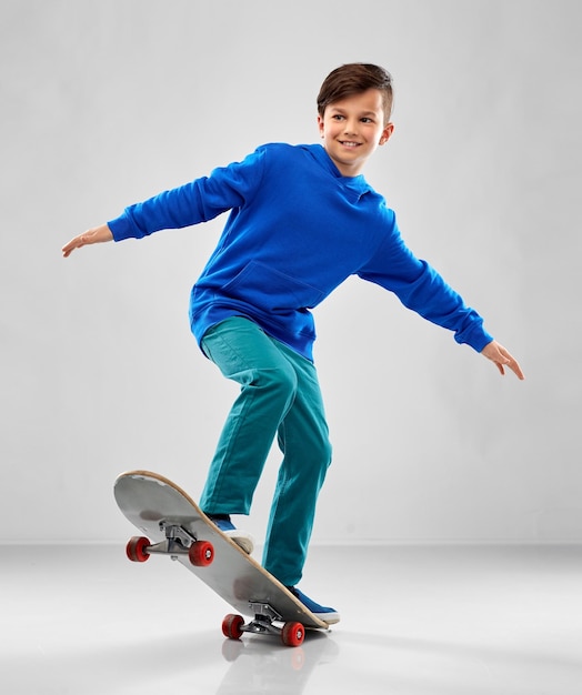 menino sorridente de capuz azul com skate