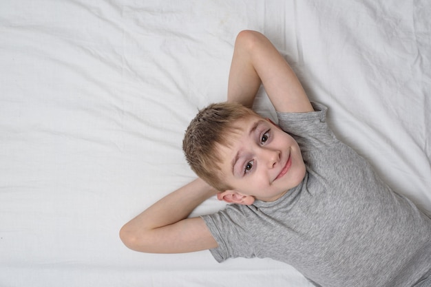 Menino sorridente deitado na cama