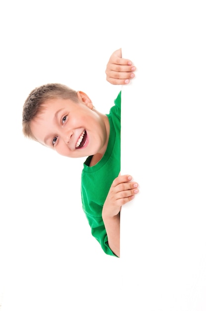 Menino sorridente e emocionalmente positivo em uma camiseta verde brilhante e posando atrás de um painel branco isolado