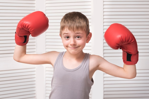 Menino sorridente em luvas de boxe.