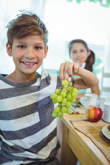 Menino sorridente segurando um cacho de uvas