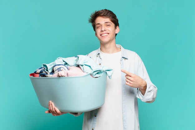 Menino sorrindo alegremente, sentindo-se feliz e apontando para o lado e para cima, mostrando o objeto no conceito de lavagem de roupas do espaço da cópia