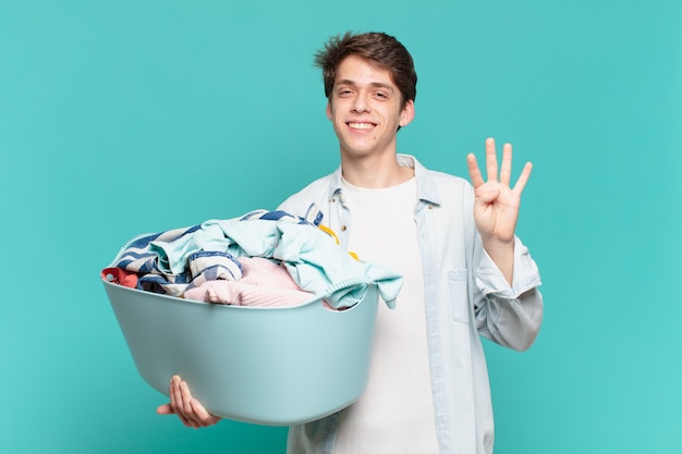 Menino sorrindo e parecendo amigável, mostrando o número quatro ou o quarto com a mão para a frente, em contagem regressiva para o conceito de lavagem de roupas