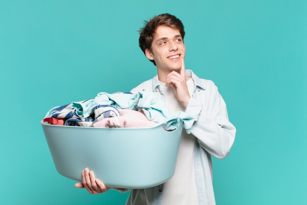 Menino sorrindo feliz e sonhando acordado ou duvidando, olhando para o lado lavando roupas conceito