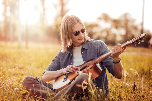 Menino tocando violão no pôr do sol natural