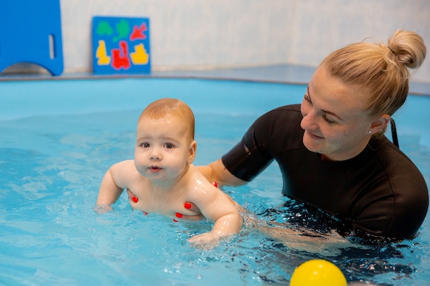 Menino treina para nadar na piscina com um treinador