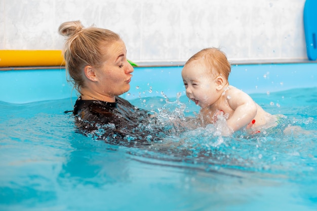 Menino treina para nadar na piscina com um treinador