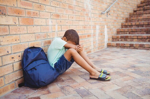 Menino triste com a cabeça nos joelhos