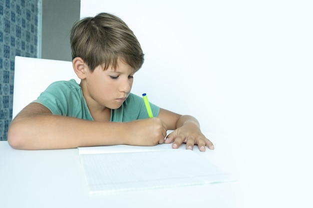 Menino triste com livro faz lição de casa da escola. de volta à escola. estudante infeliz com livros didáticos. ensino à distância.