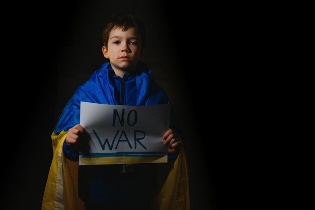 Menino triste de retrato protestando contra a guerra levanta bandeira com inscrição Stop War na bandeira amarela azul do país Ucrânia Chamada para parar a criança de guerra contra a crise de guerra na Ucrânia