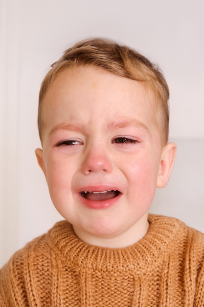 Foto menino triste está chorando. a criança pequena tem estresse, dor e está cansada.