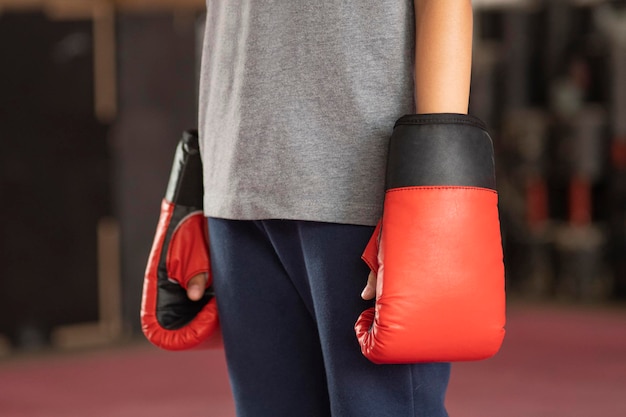Menino usa luvas de boxe vermelhas para treinar no ginásio