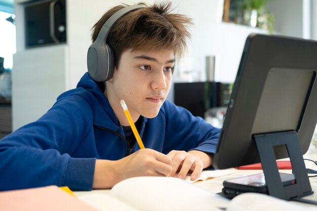 Menino usando computador e dispositivo móvel, estudando online. Educação e aprendizagem online.