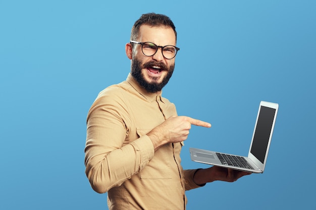 Menino usando óculos, gritando de empolgação e apontando para o novo laptop