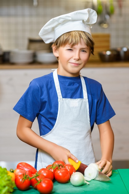 Menino vestido de cozinheiro na cozinha