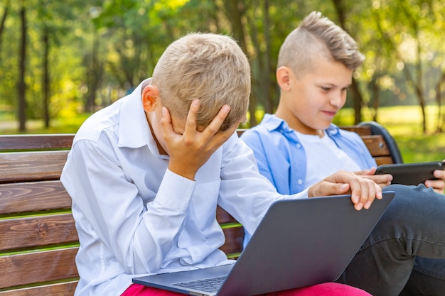 Meninos adolescentes no banco do parque se divertir e relaxar