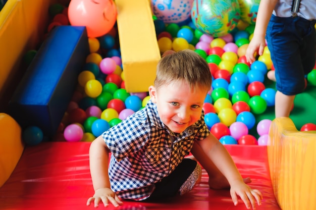 Meninos brincando no parquinho, no labirinto infantil com bolas. Bolas multicoloridas.