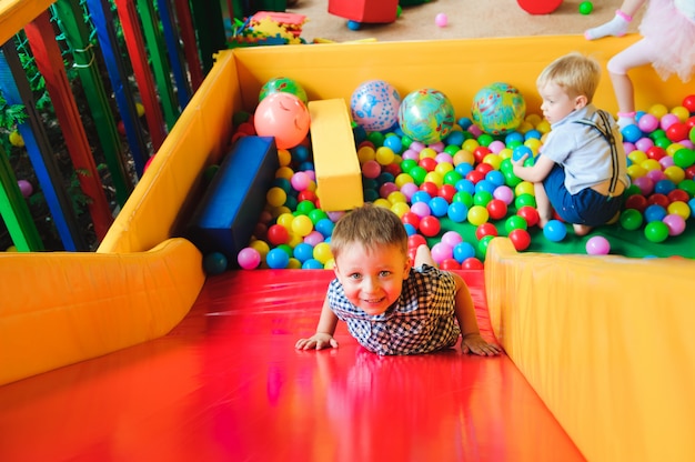 Meninos brincando no playground, no labirinto infantil com bola
