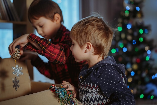 Meninos caucasianos bonitos decorando a árvore de Natal com decorações cintilantes