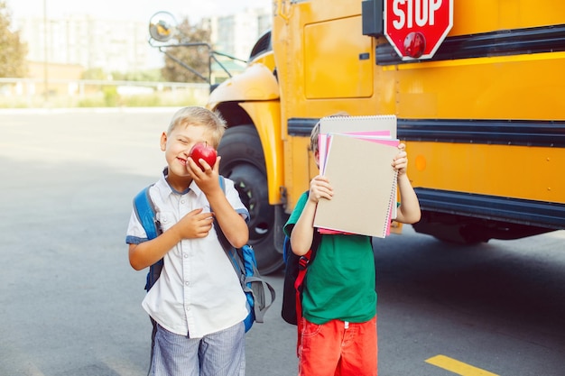 Foto meninos com livros e maçãs a caminhar no autocarro escolar