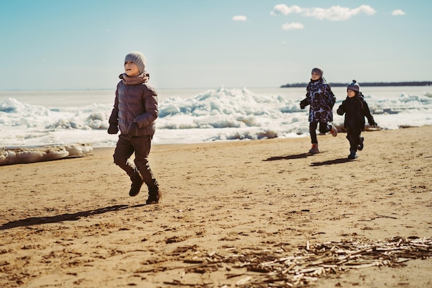 Meninos correndo ao longo da praia do Golfo da Finlândia coberta de gelo Imagem com foco seletivo