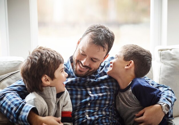 Meninos da casa da família e pai com abraço no sofá para conversar sobre amor ou vínculo para o desenvolvimento da infância pessoas felizes relaxam ou brincam juntas na sala de estar para diversão, felicidade ou tempo de qualidade em casa