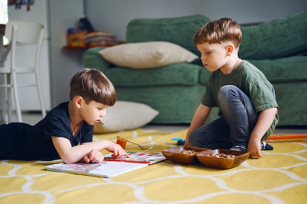 meninos da pré-escola lendo livro e brincando juntos