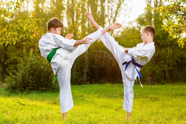 Meninos de quimono fazendo exercícios de caratê ao ar livre