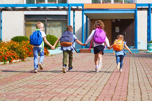 Meninos e meninas correndo para a escola primária.