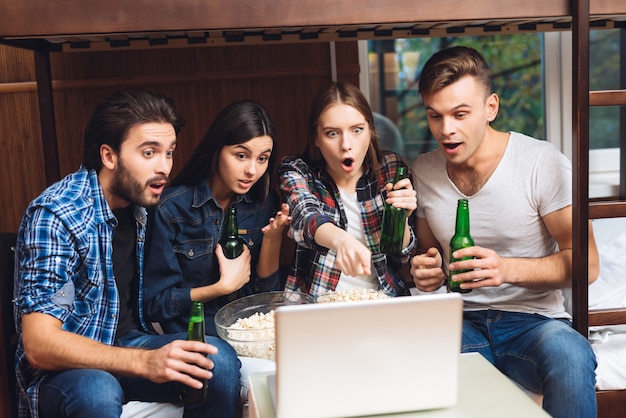 Meninos e meninas estão assistindo filme no laptop com cerveja.