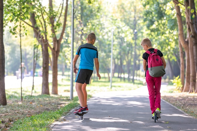 Meninos felizes com patins e scooter no parque