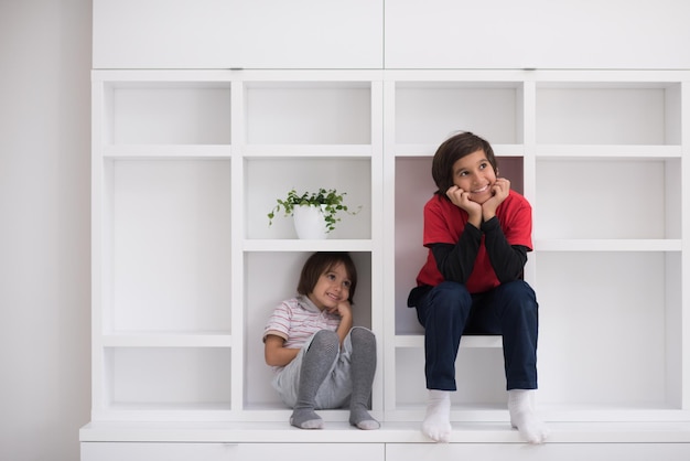 meninos felizes estão se divertindo enquanto posam em uma prateleira em uma nova casa moderna