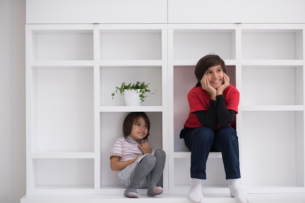 Meninos felizes estão se divertindo enquanto posam em uma prateleira em uma nova casa moderna