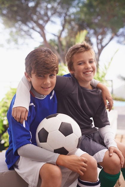 Meninos serão meninos foto de dois meninos sentados do lado de fora com uma bola de futebol