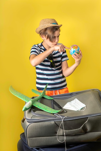 Meninos turistas em roupas de verão planejando um globo de sua rota de viagem, tempo de coronavírus