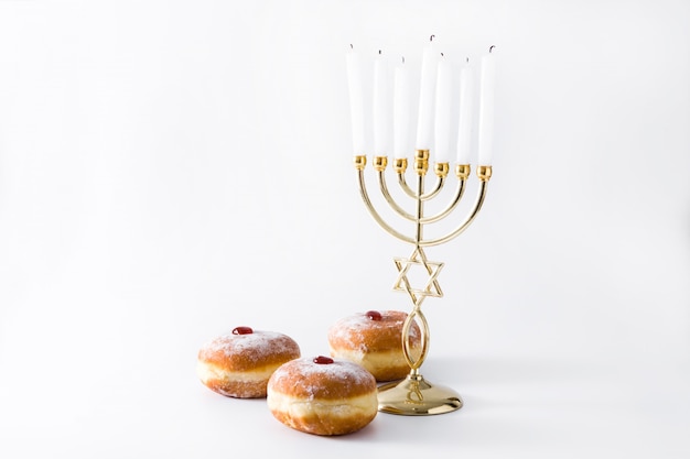 Menorá de hanukkah judaica e rosquinhas sufganiyot na superfície branca