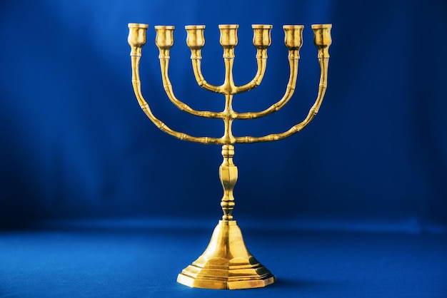 Menora de Hanukkah dorada sobre fondo azul Estandarte de fiesta judía con espacio de copia Menora de vela religiosa ritual antigua