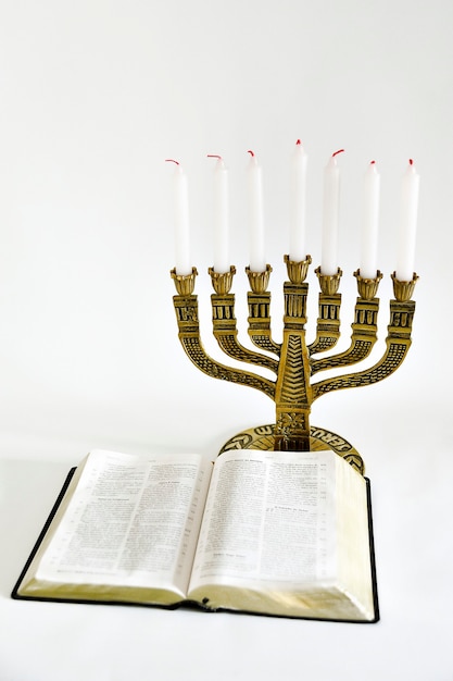 Menorah y biblia abierta con 7 velas apagadas en blanco