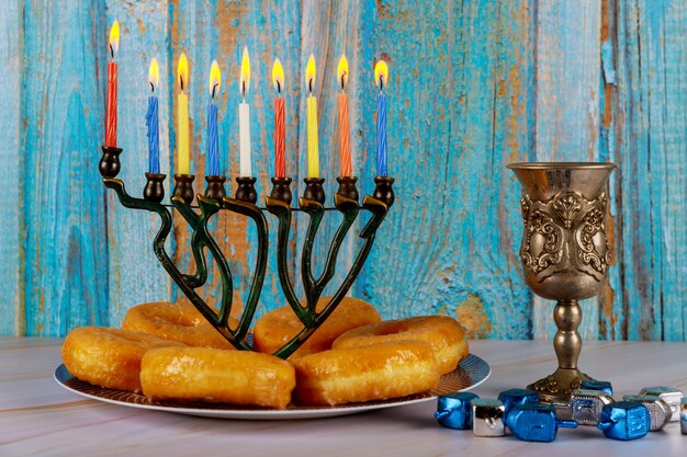 Menorah con velas encendidas, donas y copa de vino