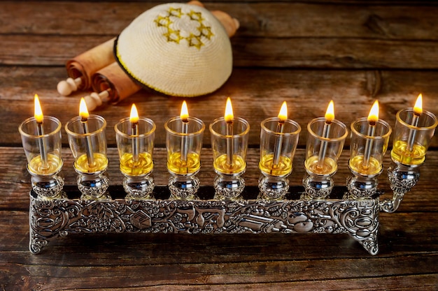 Menorah vintage con velas de aceite encendidas y kipá con totah para Hanukkah. Fiesta judía.